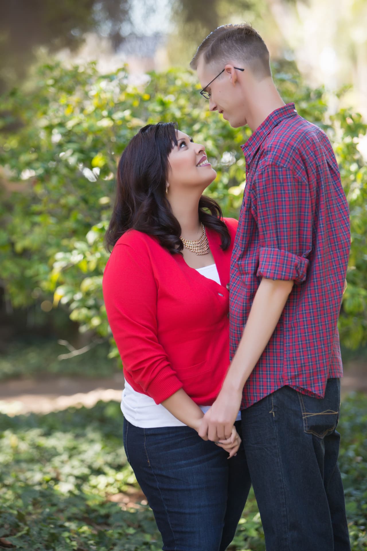 Engaged couple holding hands and smiling in a garden