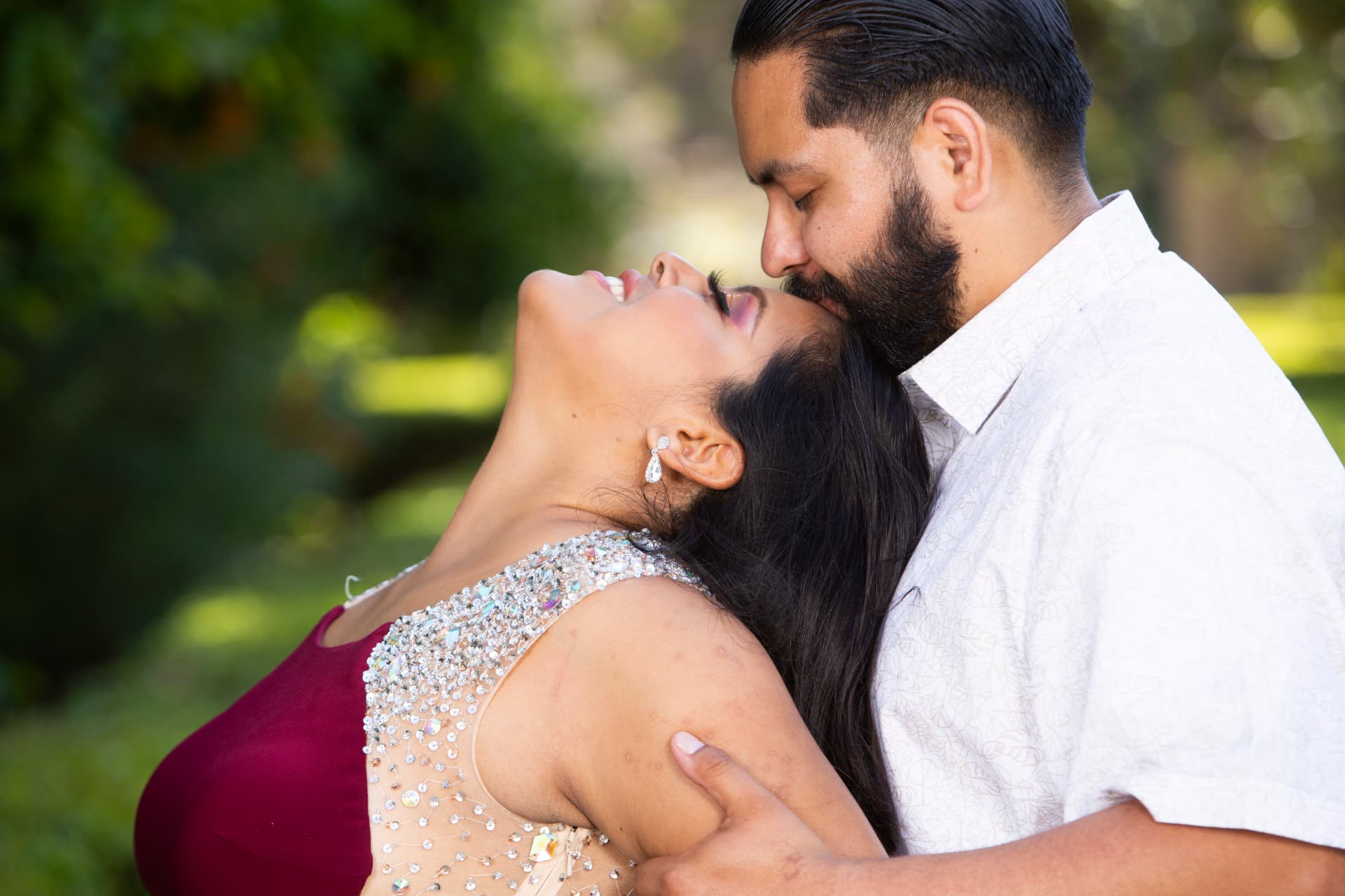 Engaged couple sharing a joyful embrace in a sunlit garden