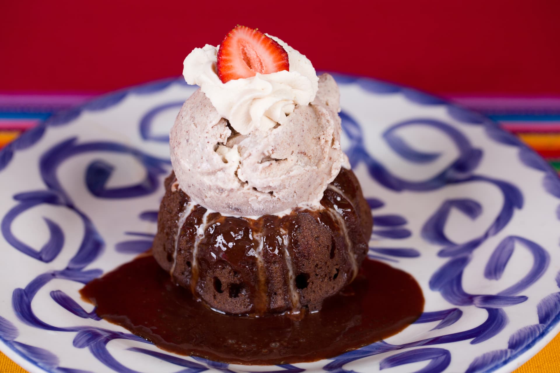 Warm chocolate cake topped with ice cream, whipped cream, and a strawberry