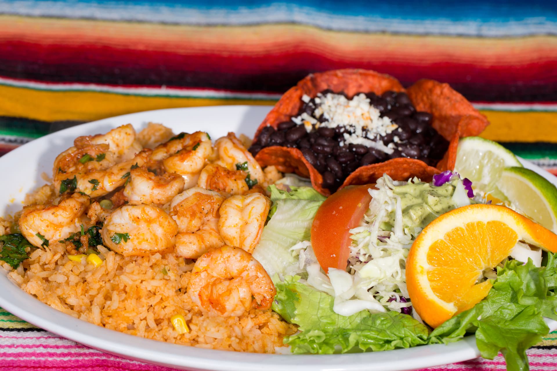 Seasoned shrimp and Mexican rice served with black beans, salad, and citrus