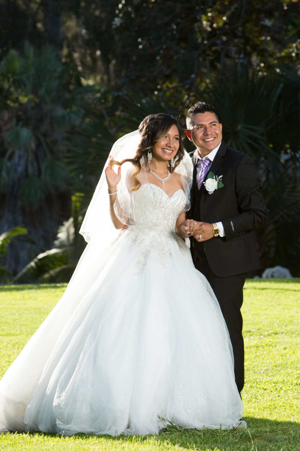 Smiling bride and groom standing together in a bright garden