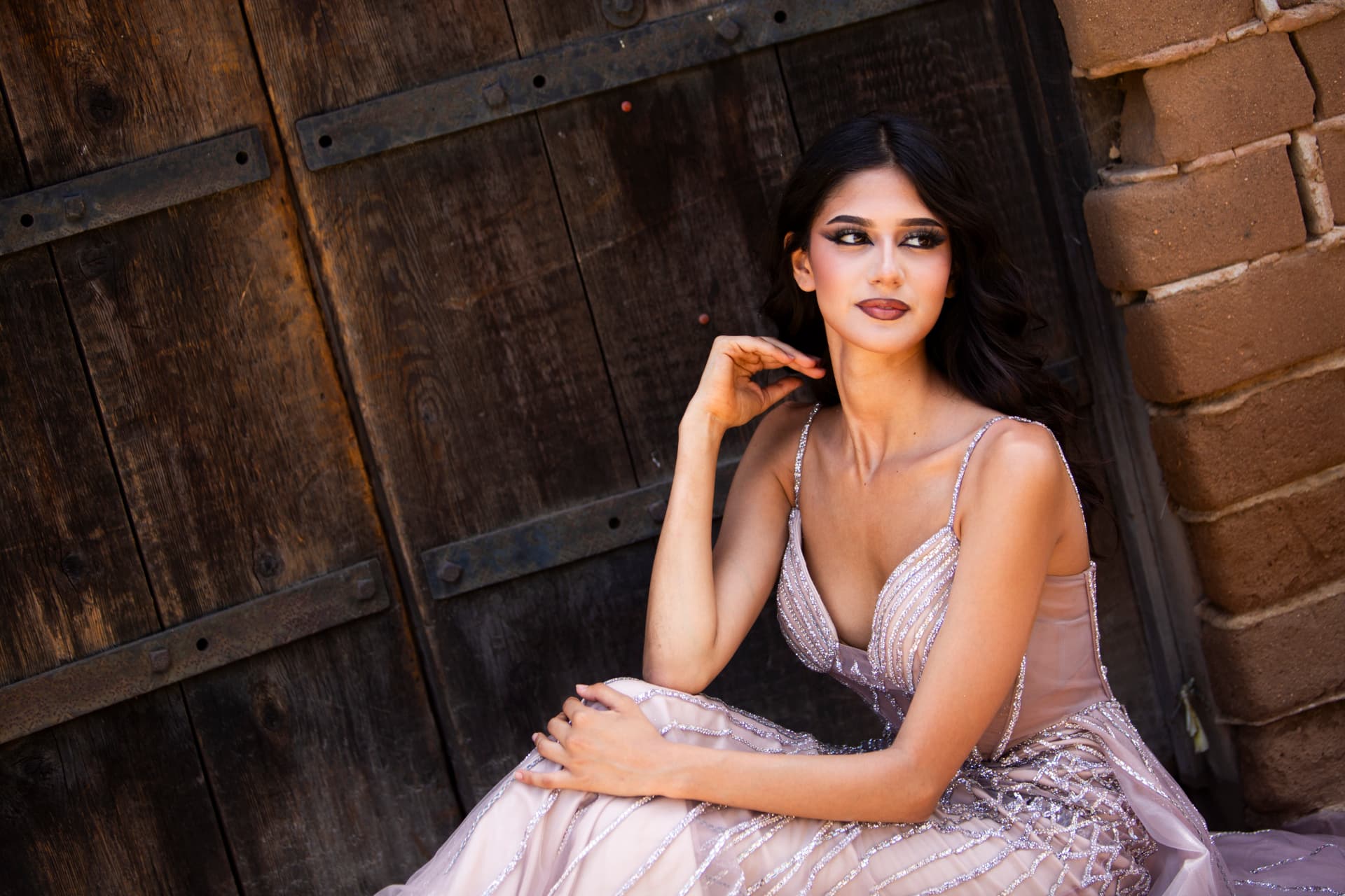 Editorial portrait of a seated model looking aside in a shimmering gown
