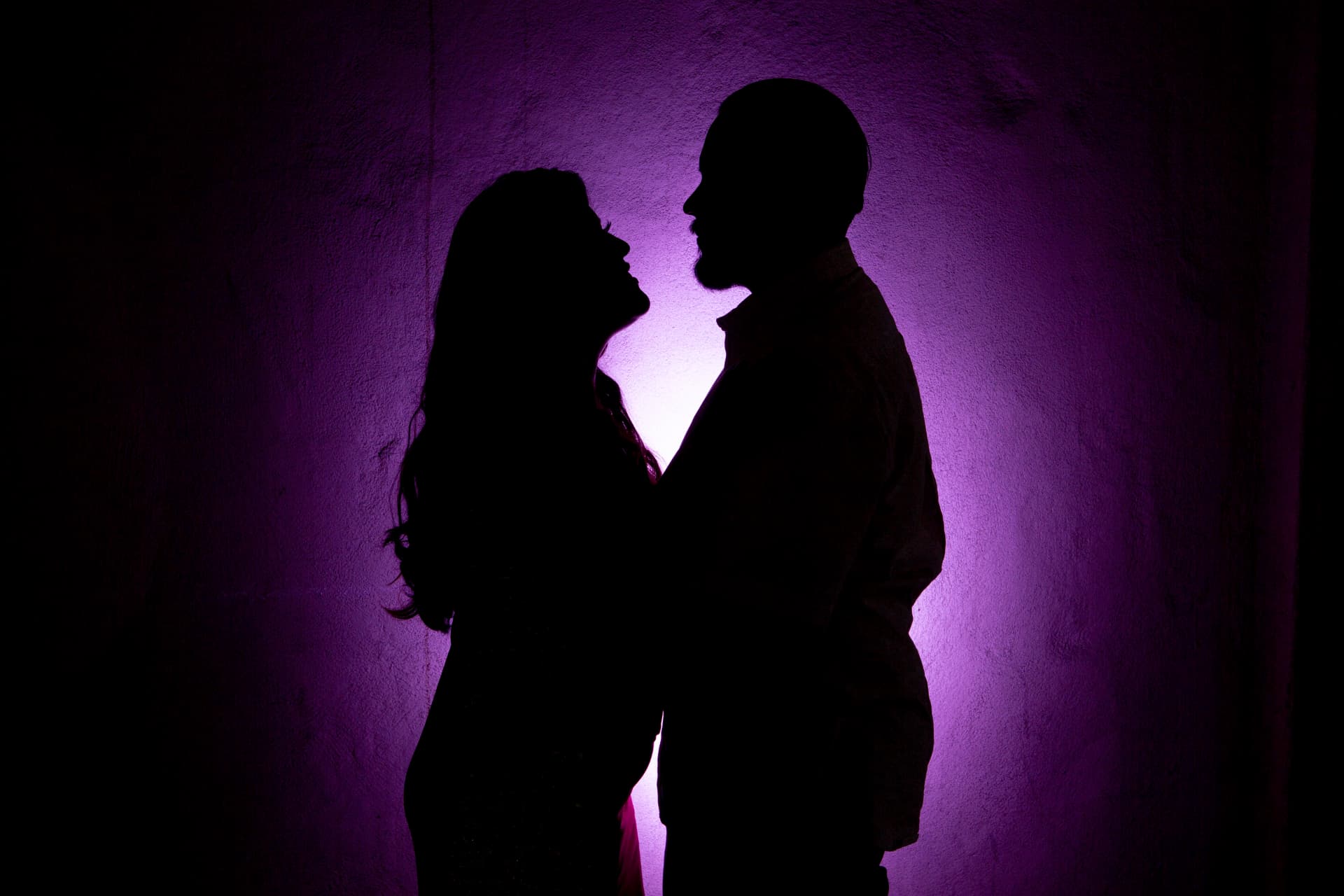 Engaged couple silhouetted against dramatic purple light