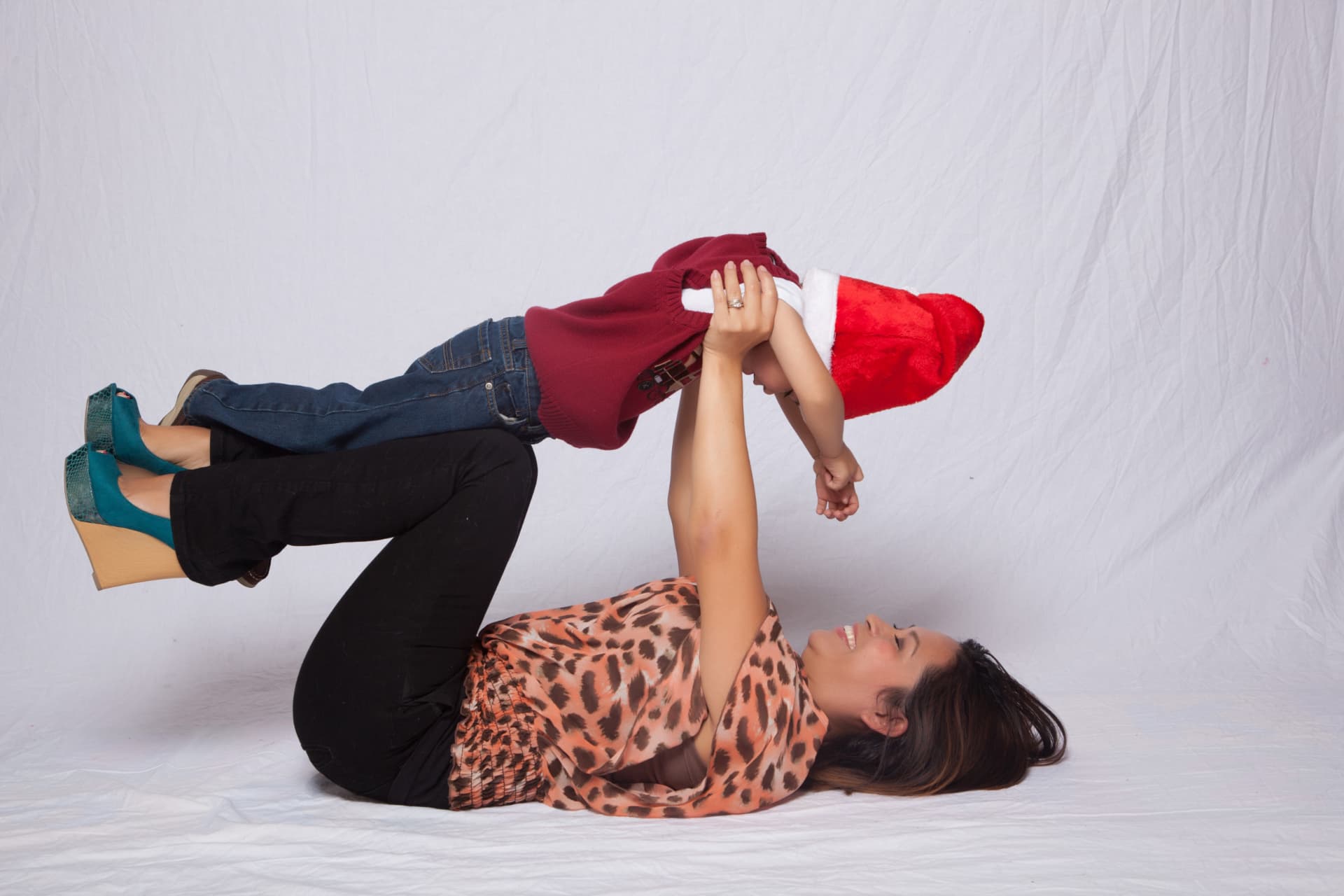 Mother lying down and lifting her young son during a playful portrait