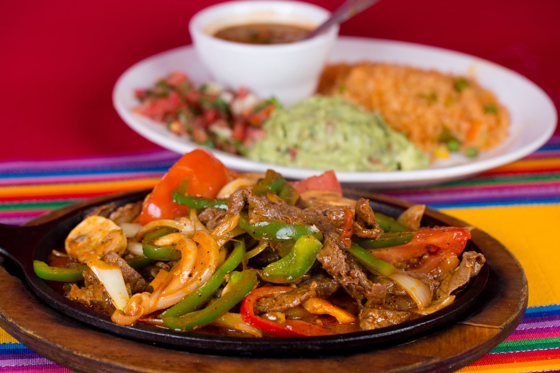 Sizzling beef fajitas with peppers, onions, rice, guacamole, and pico de gallo