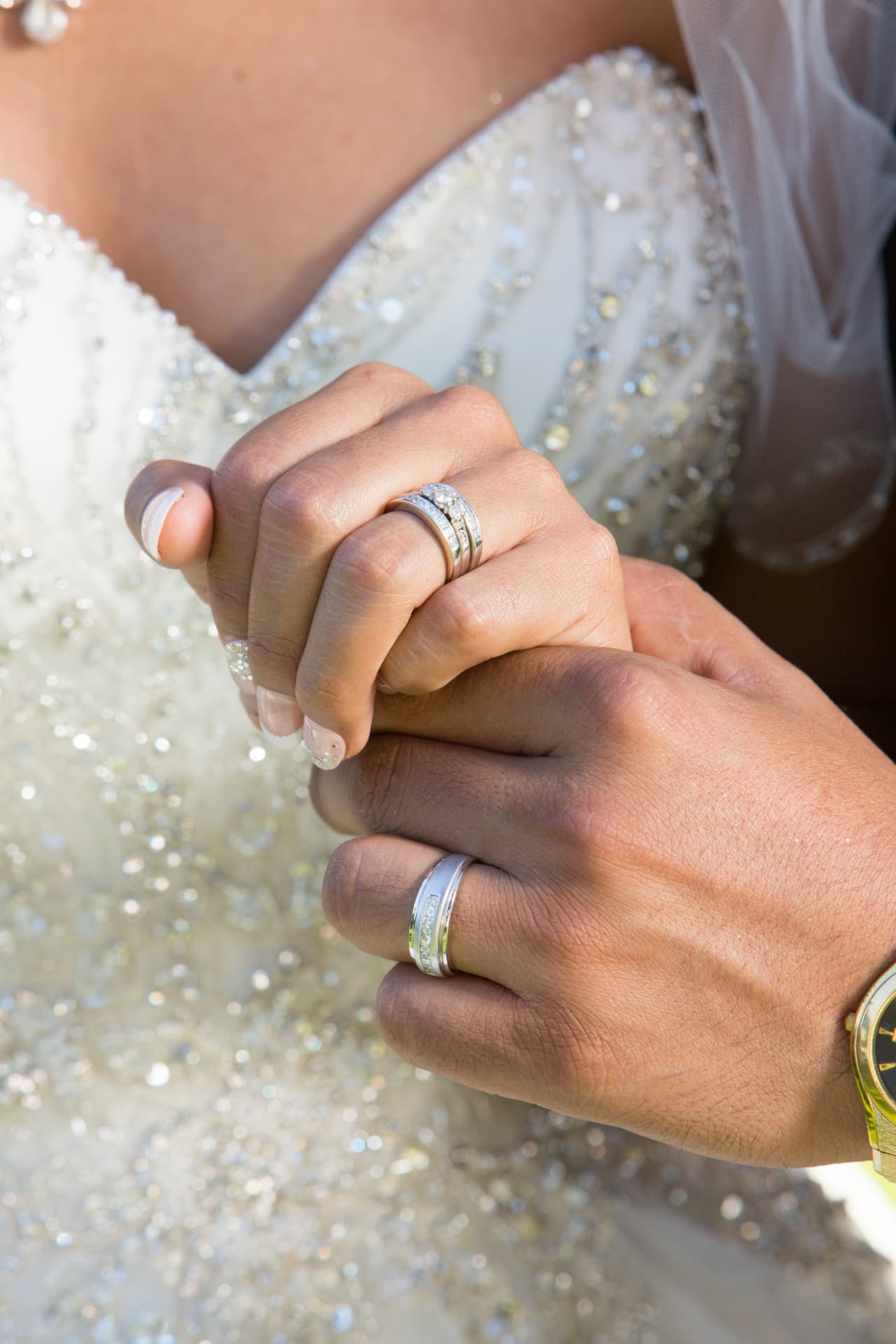 Close-up of newlyweds holding hands and showing their wedding rings