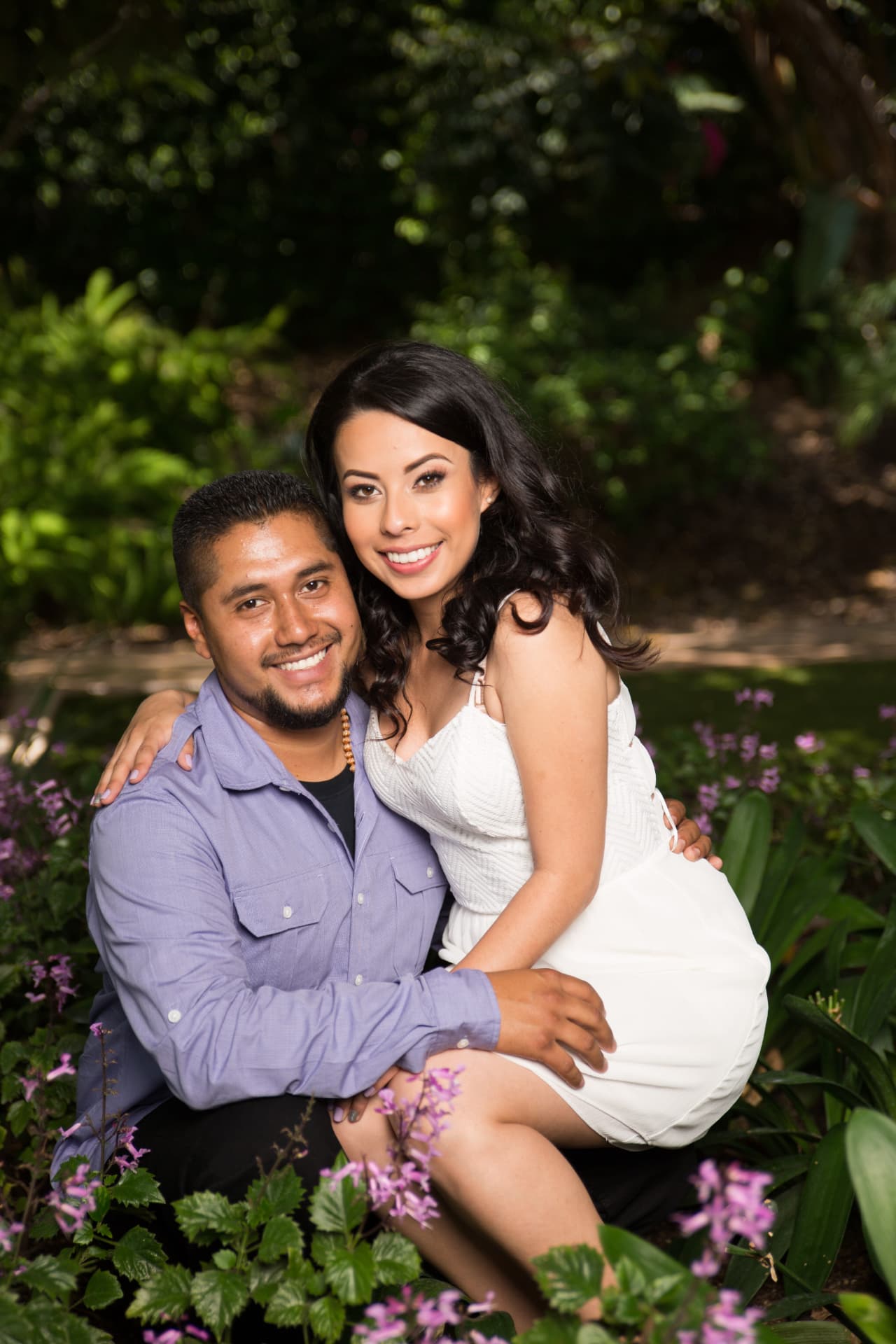 Engaged couple smiling together among purple flowers