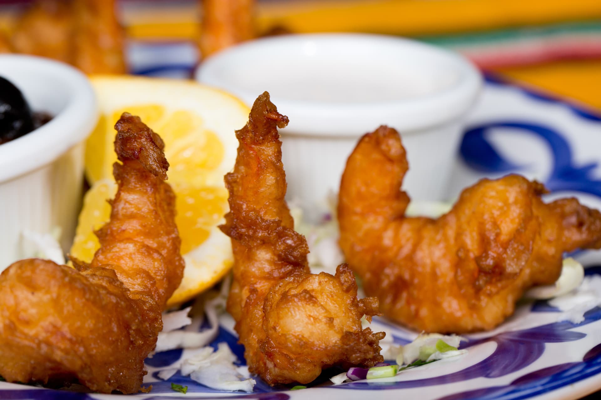 Close-up of golden fried shrimp with citrus and dipping sauces