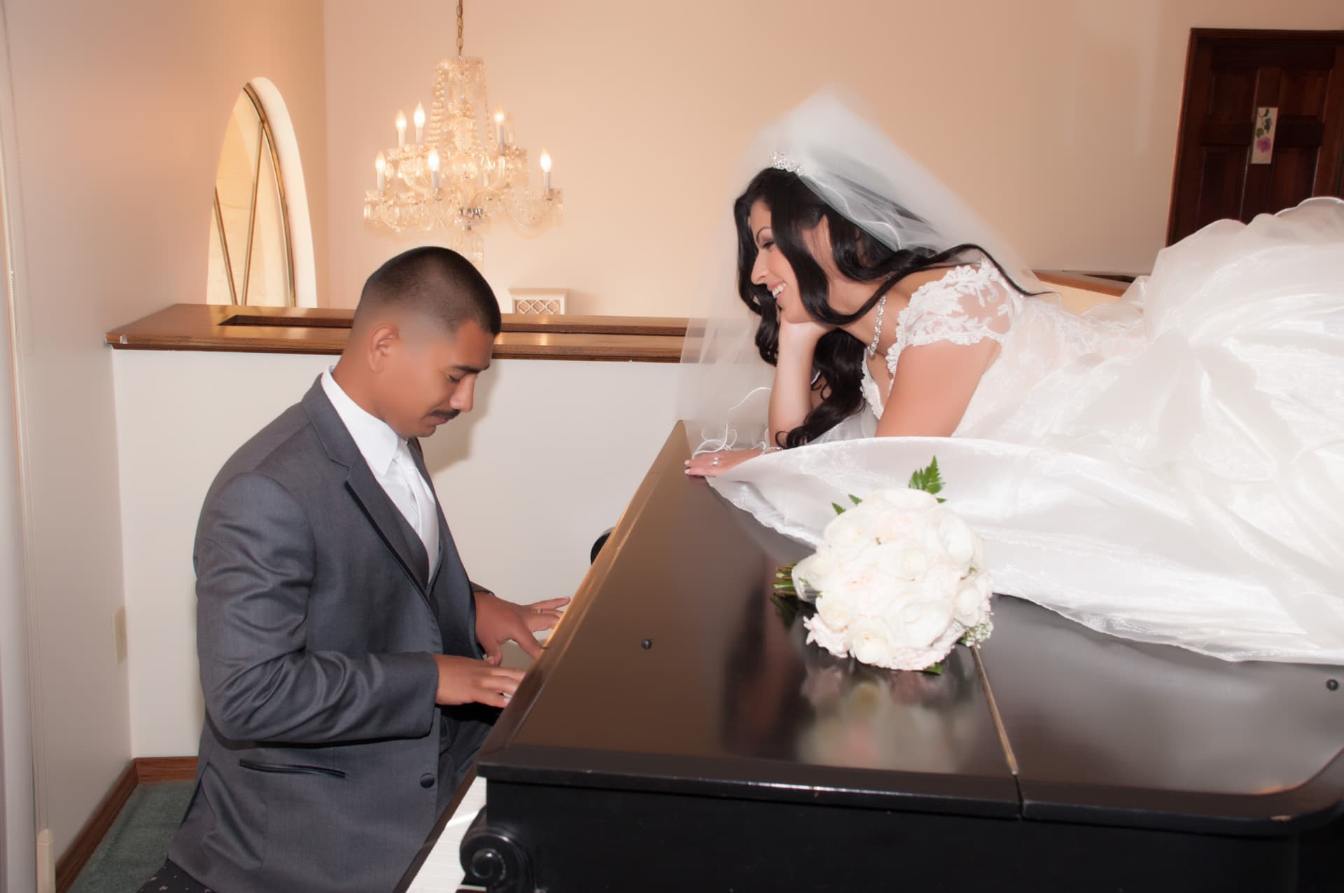 Groom playing a grand piano while his bride smiles from above