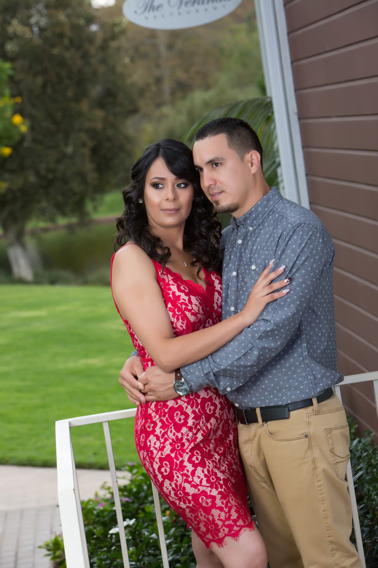 Engaged couple embracing beside a garden venue