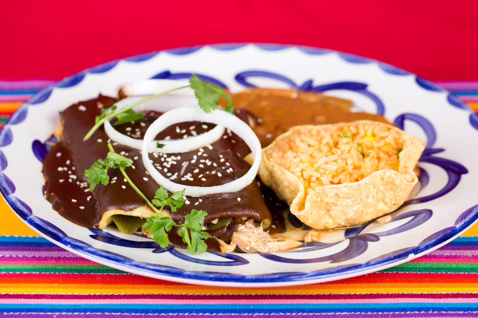 Chicken enchiladas covered in mole sauce with rice and beans