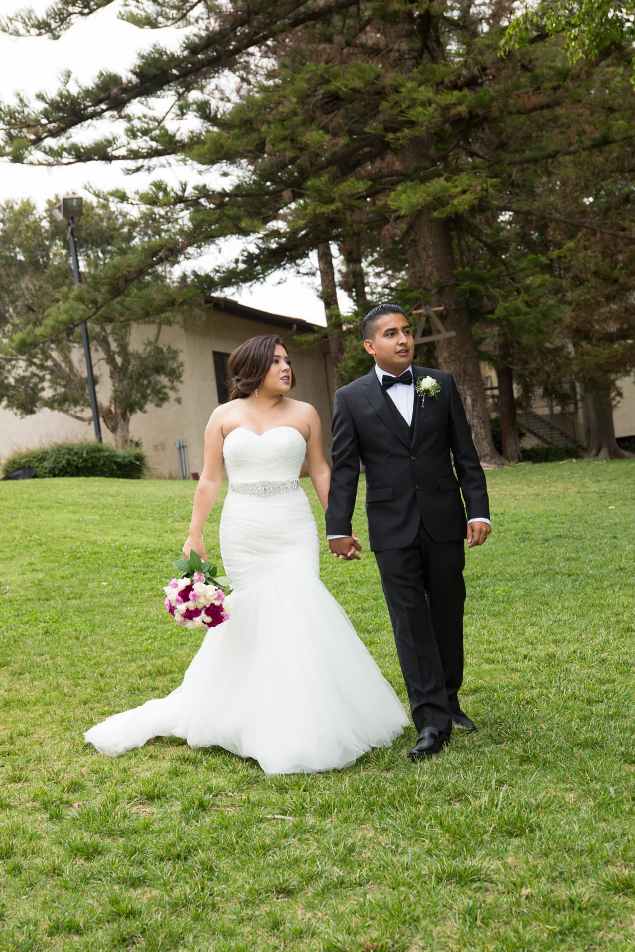 Bride and groom walking hand in hand across a green lawn