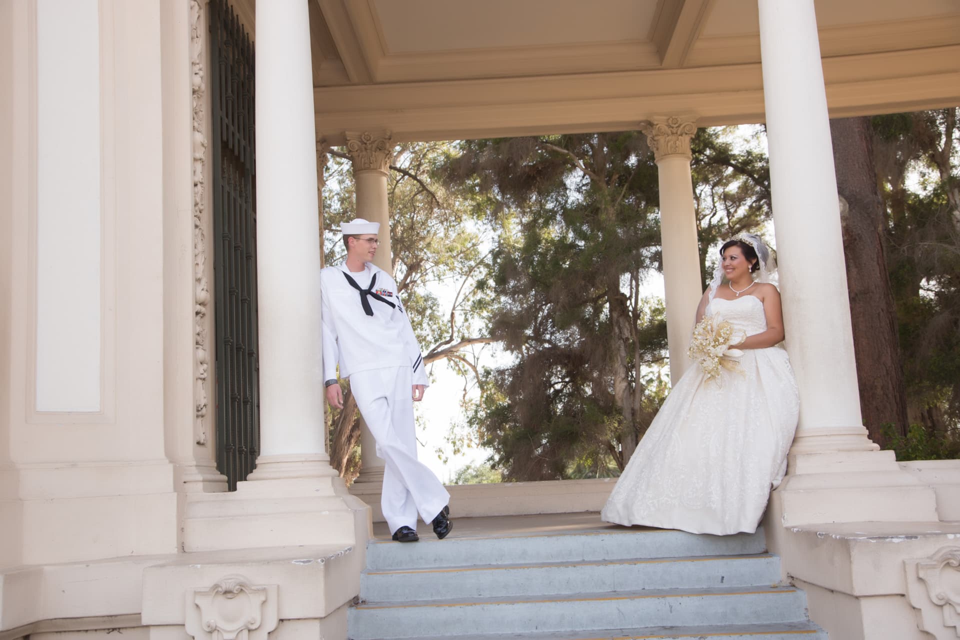 Navy groom and bride exchanging smiles between grand classical columns
