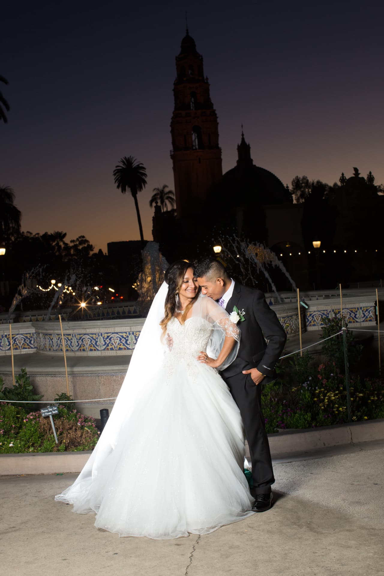 Bride and groom sharing a tender moment beside a fountain at twilight