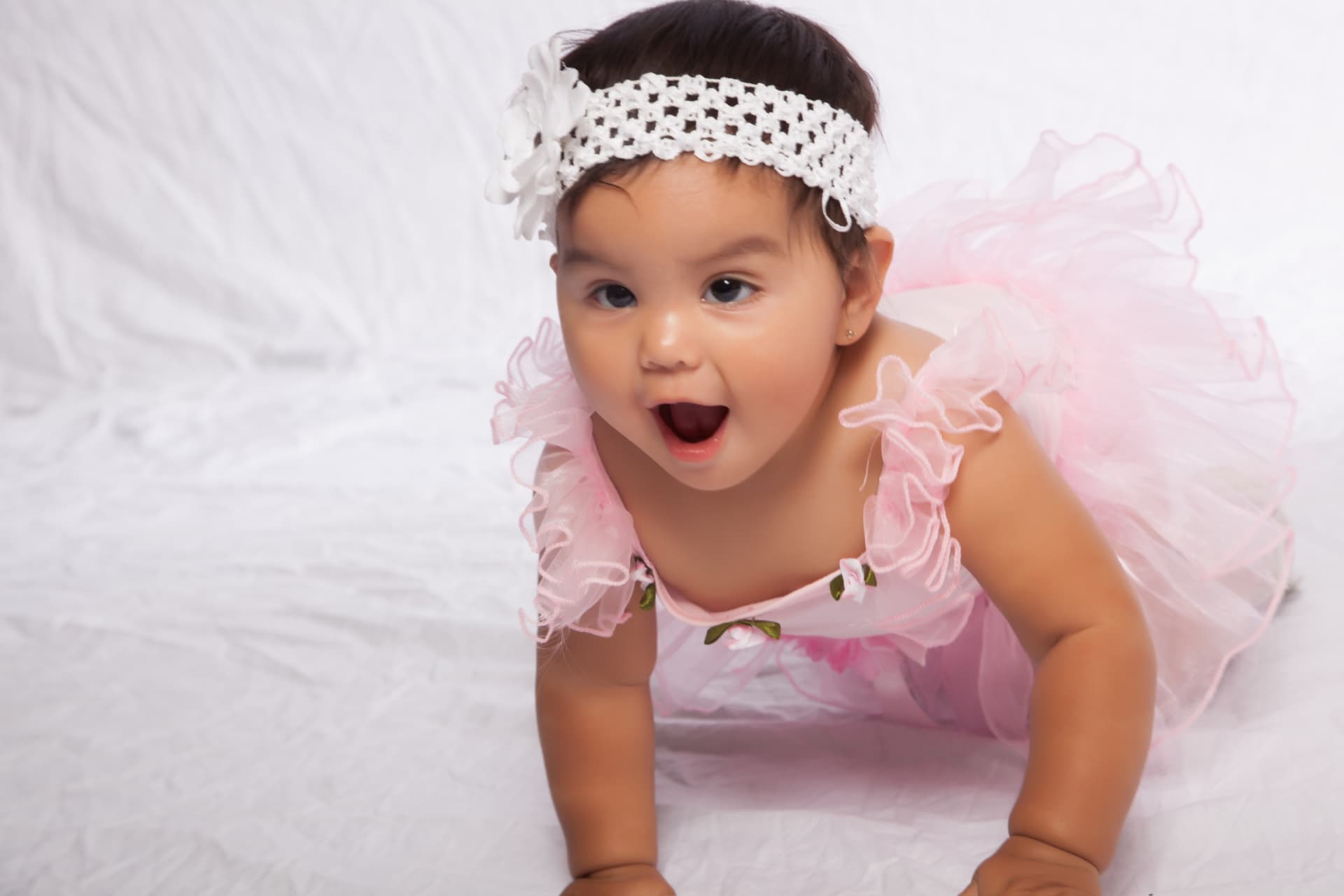 Baby girl in a pink ruffled dress and white floral headband