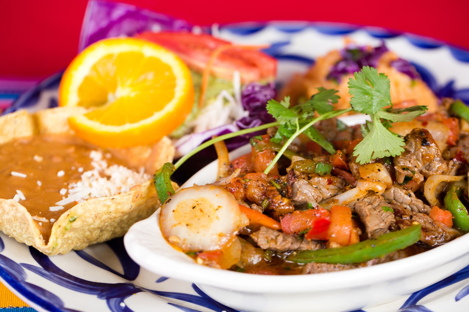 Sizzling beef fajitas with peppers, onions, rice, beans, and fresh orange