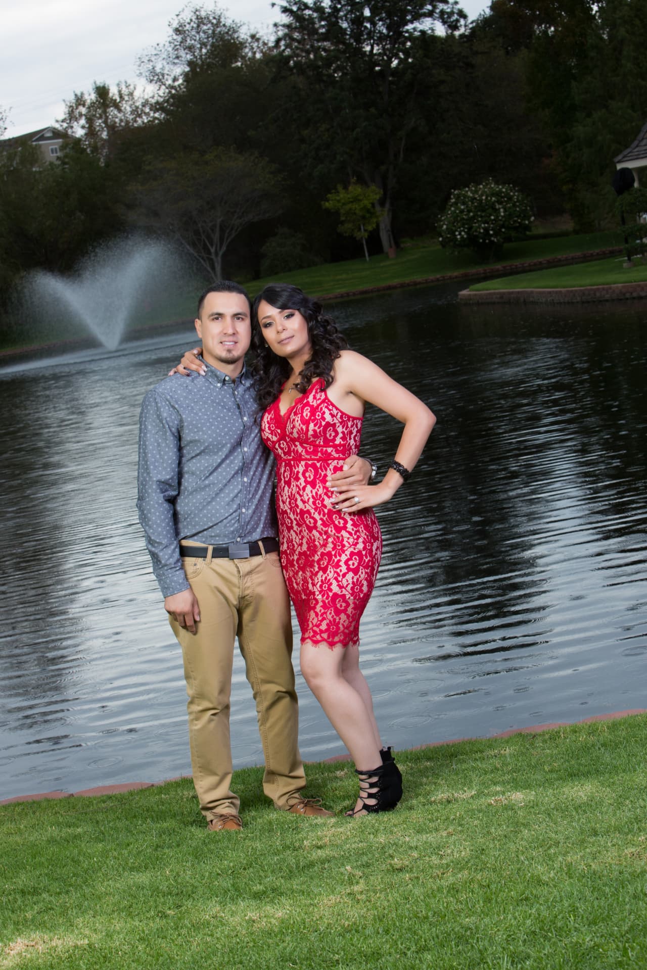 Engaged couple posing beside a lakeside fountain