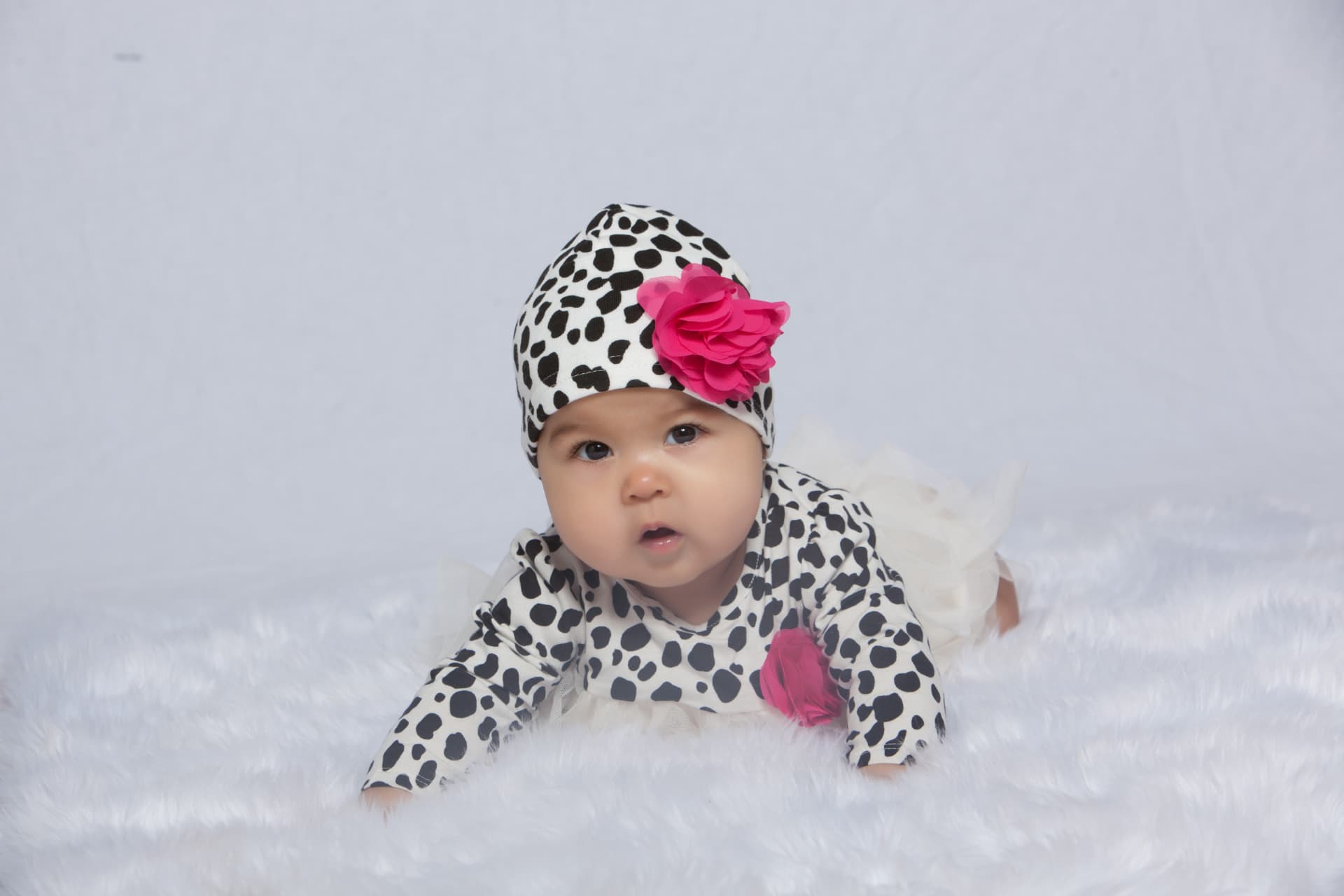 Baby girl crawling in a spotted outfit with a bright pink flower