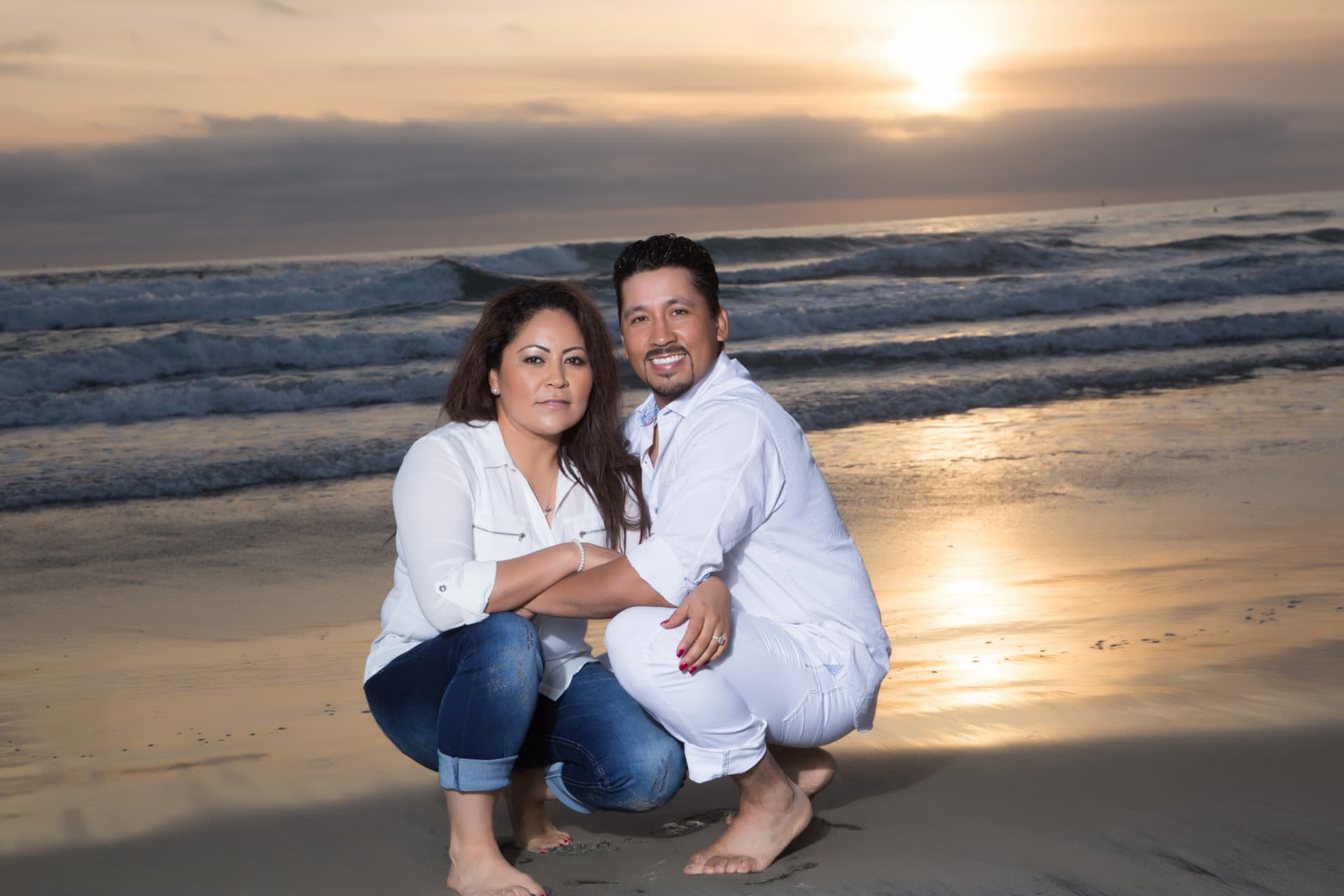 Engaged couple posing together at sunset on the beach