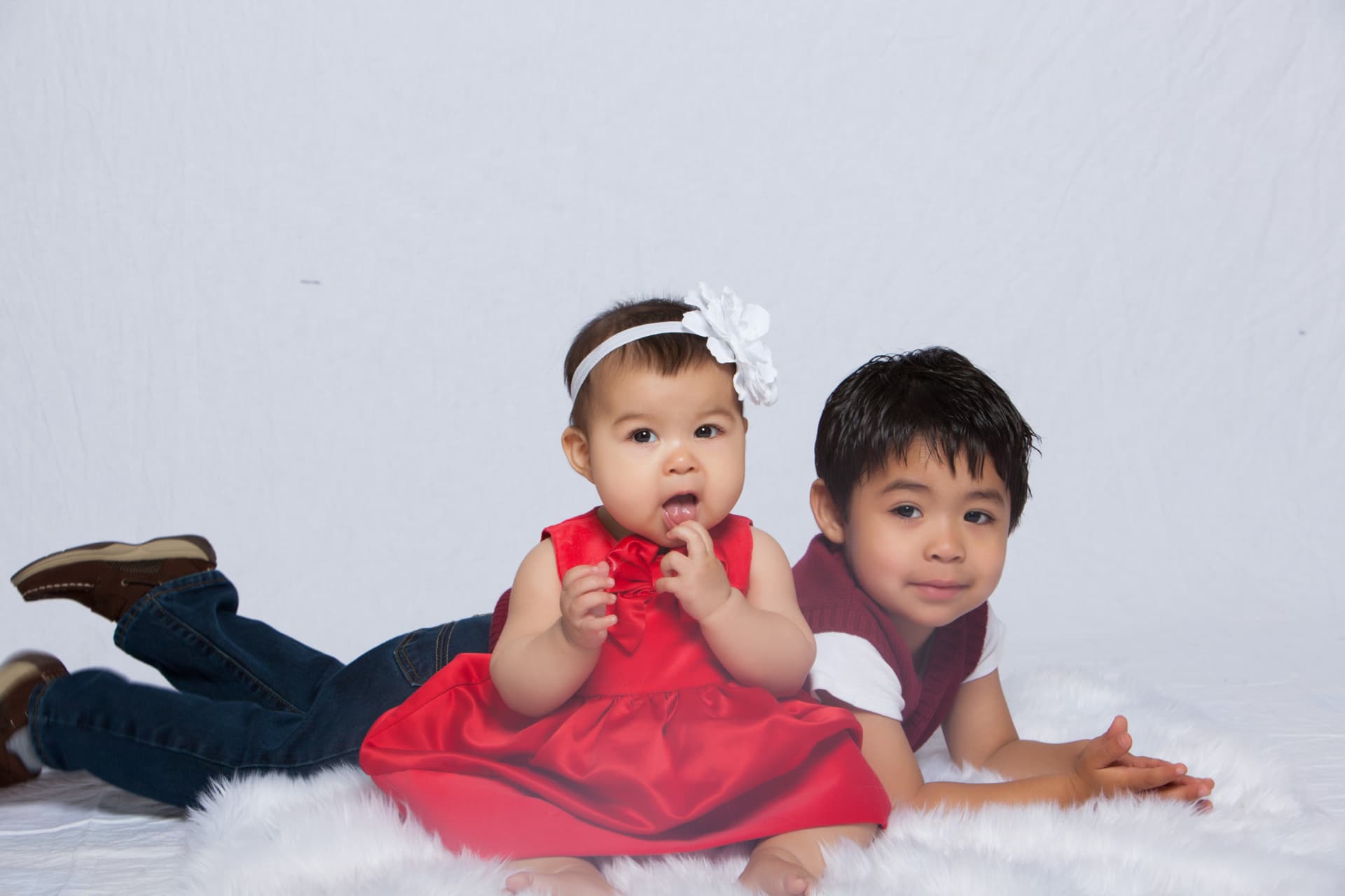 Baby girl in a red dress posing with her older brother