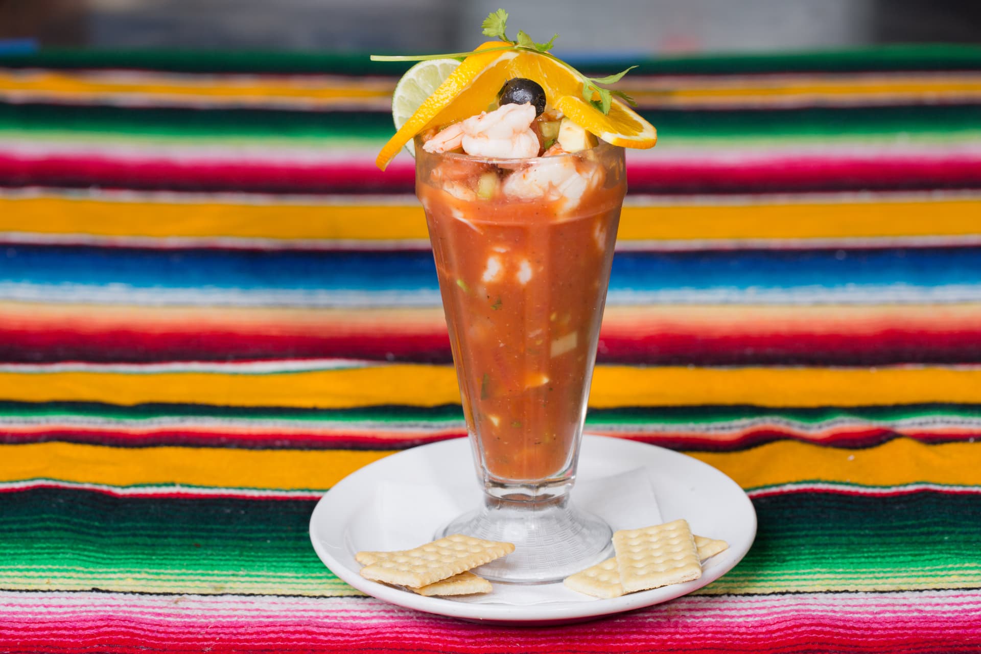 Mexican shrimp cocktail garnished with orange, lime, olives, and cilantro