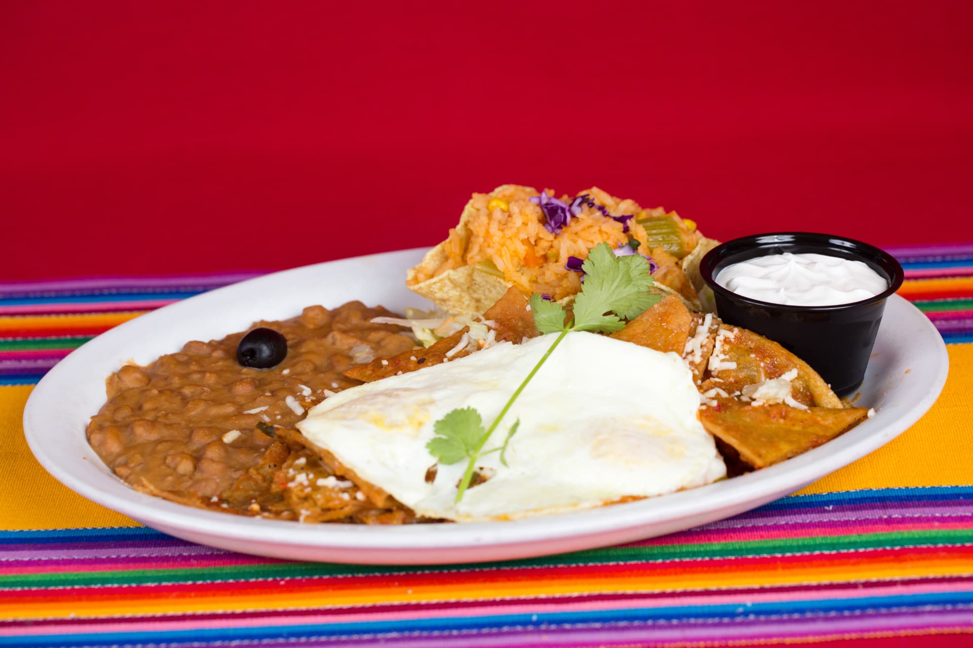Mexican breakfast plate with eggs, beans, rice, tortilla chips, and crema