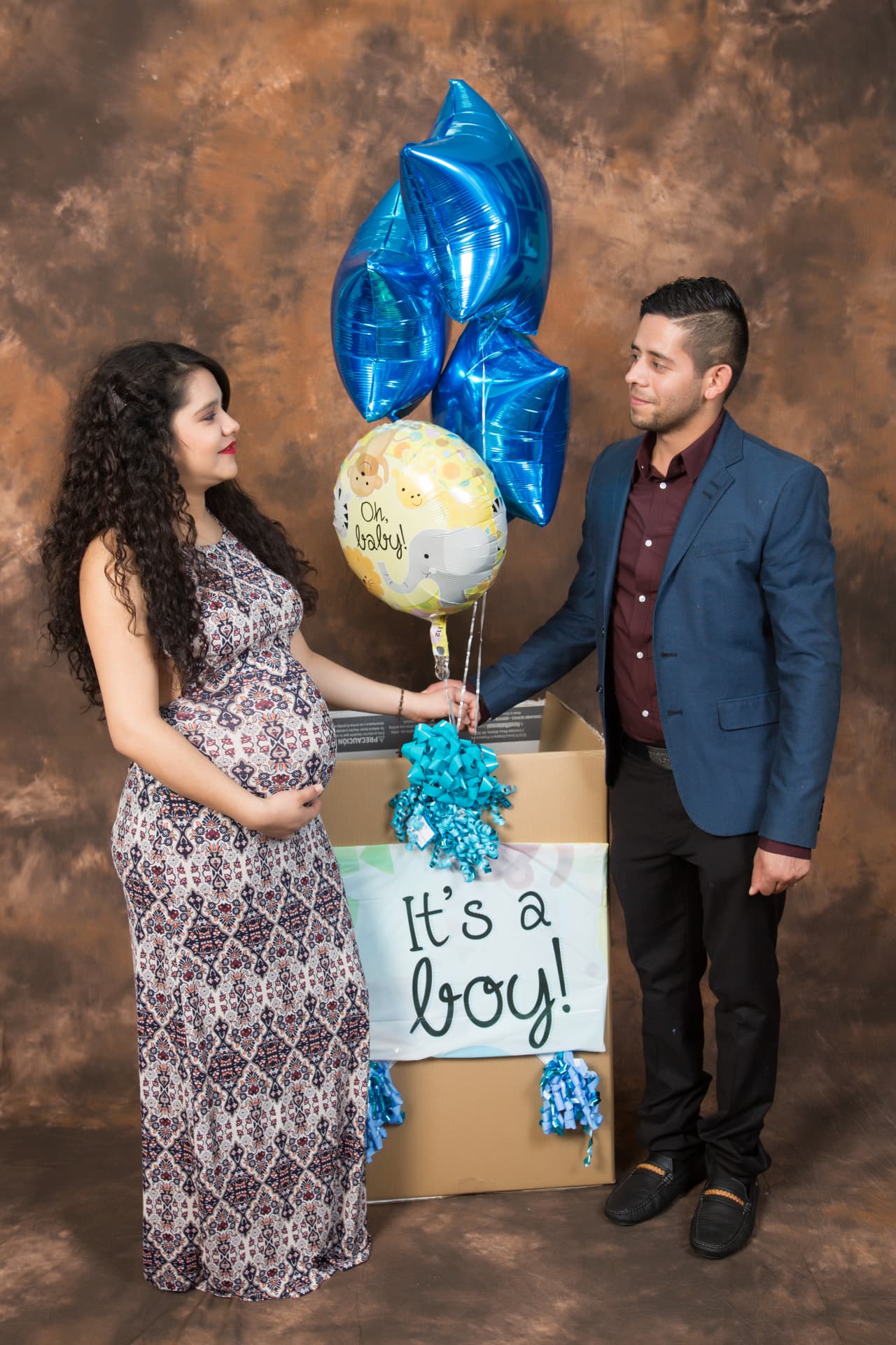 Expectant parents celebrating their baby boy with blue balloons