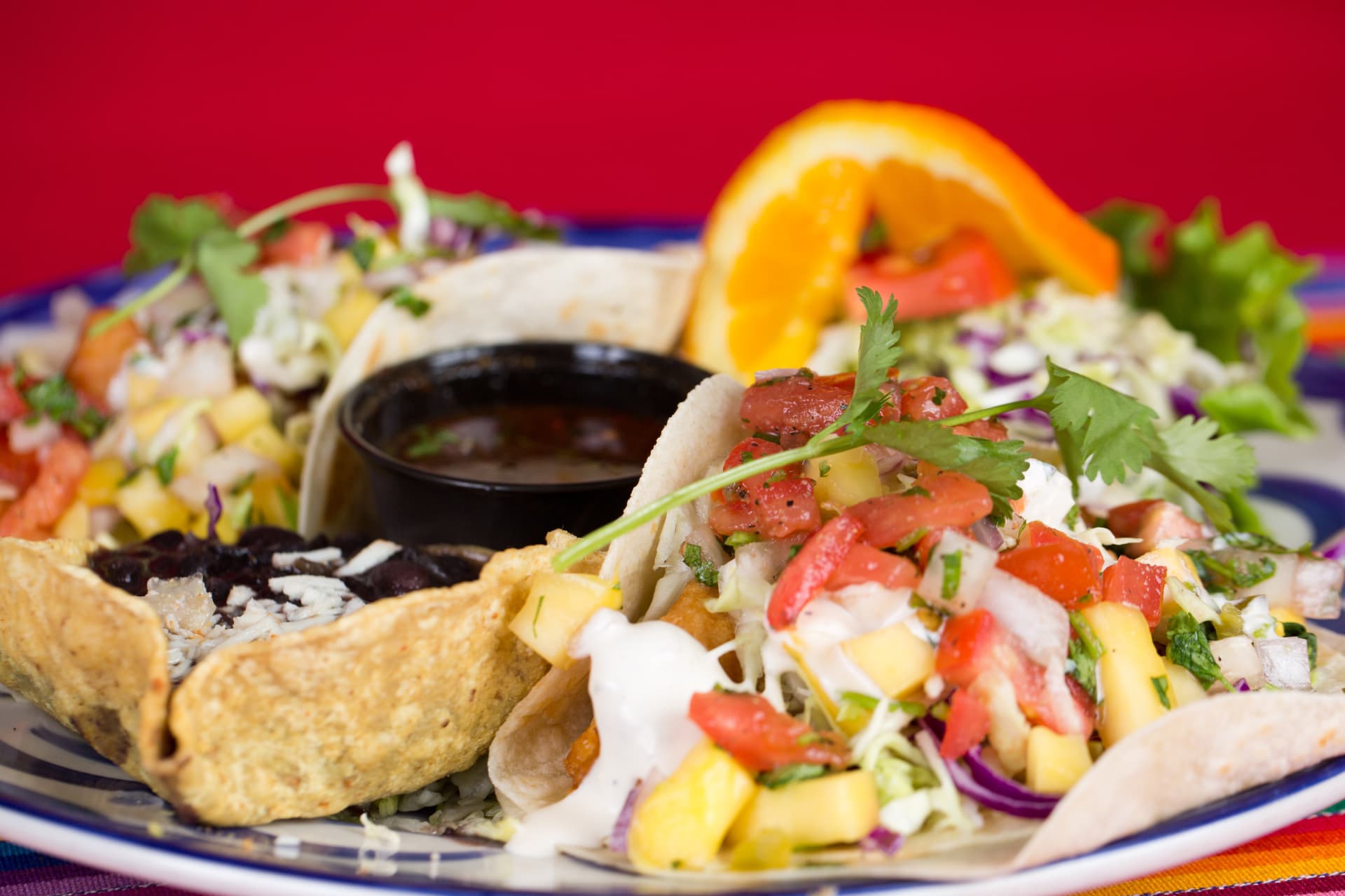 Fish tacos topped with fresh mango salsa and cilantro beside rice and beans