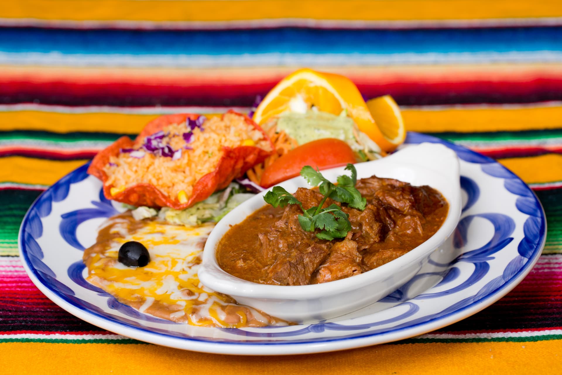 Rich Mexican beef stew served with rice, beans, salad, and guacamole