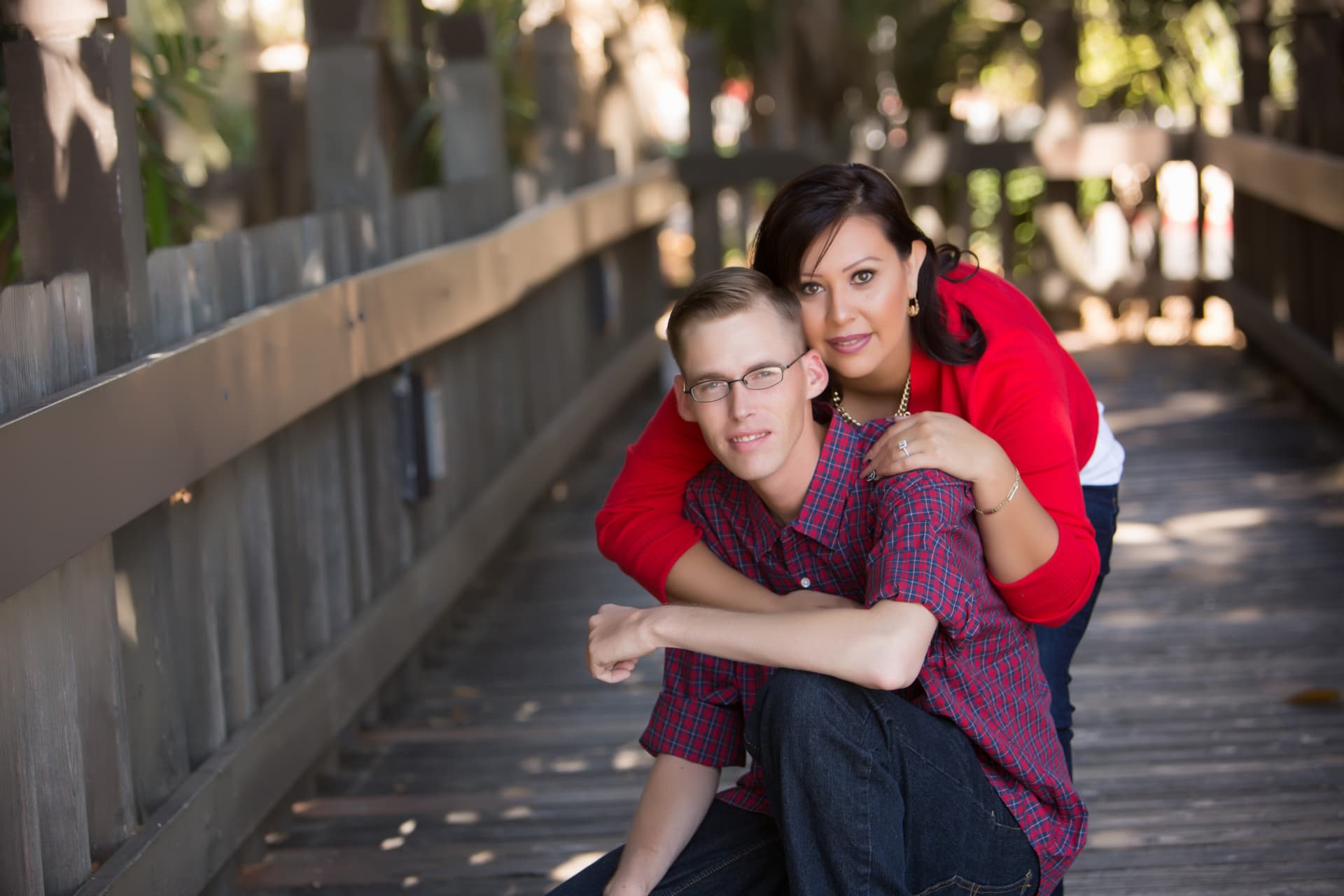 Engaged couple posing together on a shaded boardwalk