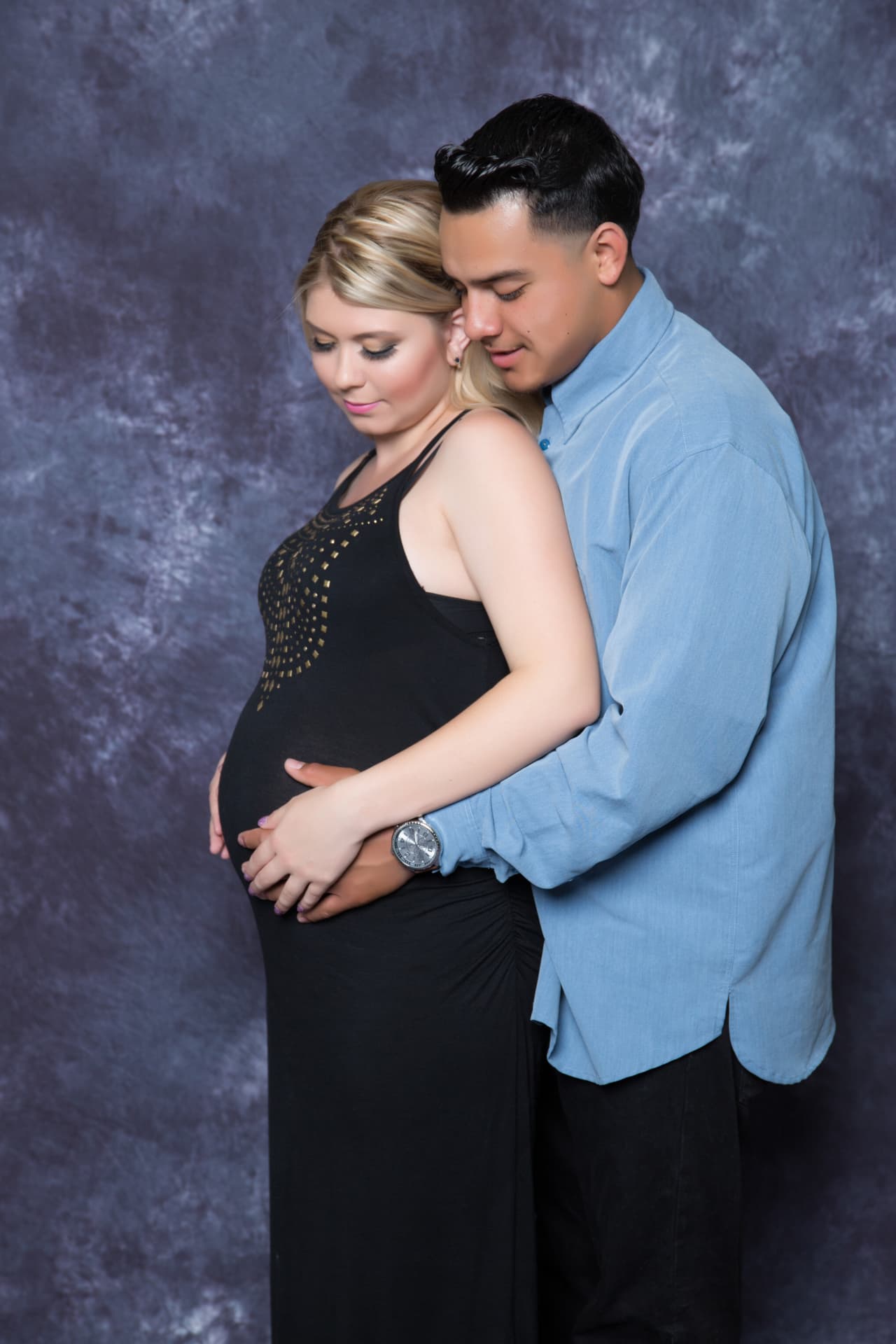 Expectant father embracing the mother and cradling her baby bump