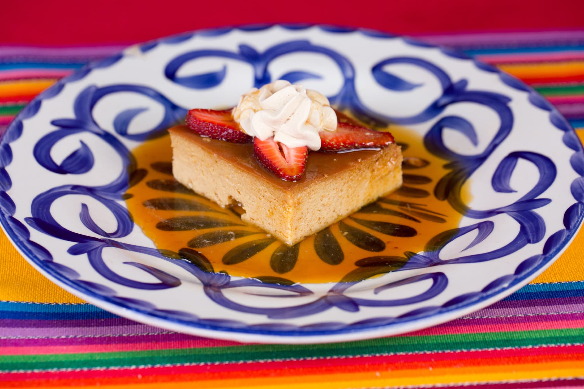 Caramel flan topped with sliced strawberries and whipped cream