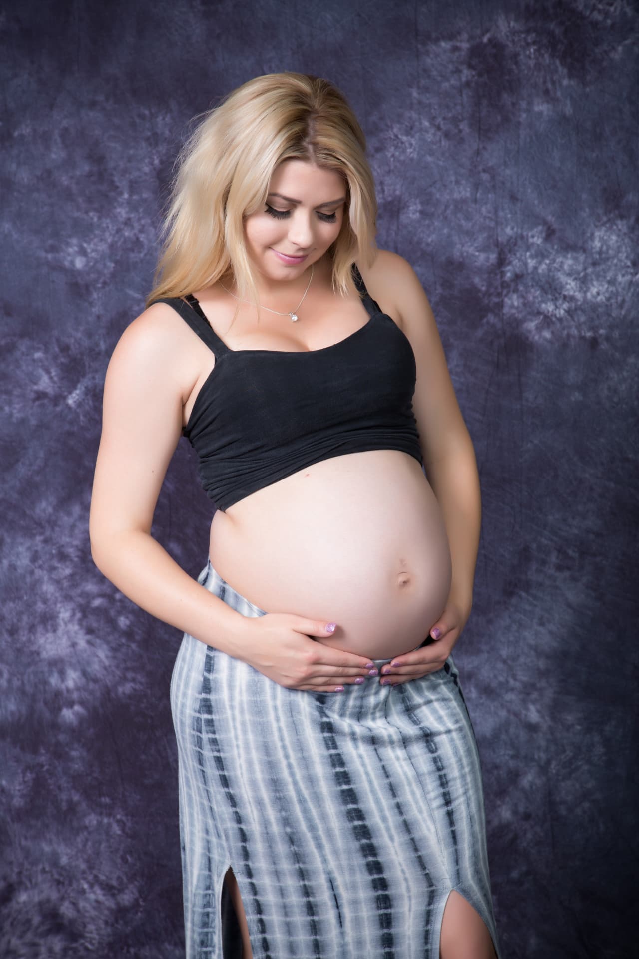 Expectant mother cradling her baby bump in a studio portrait