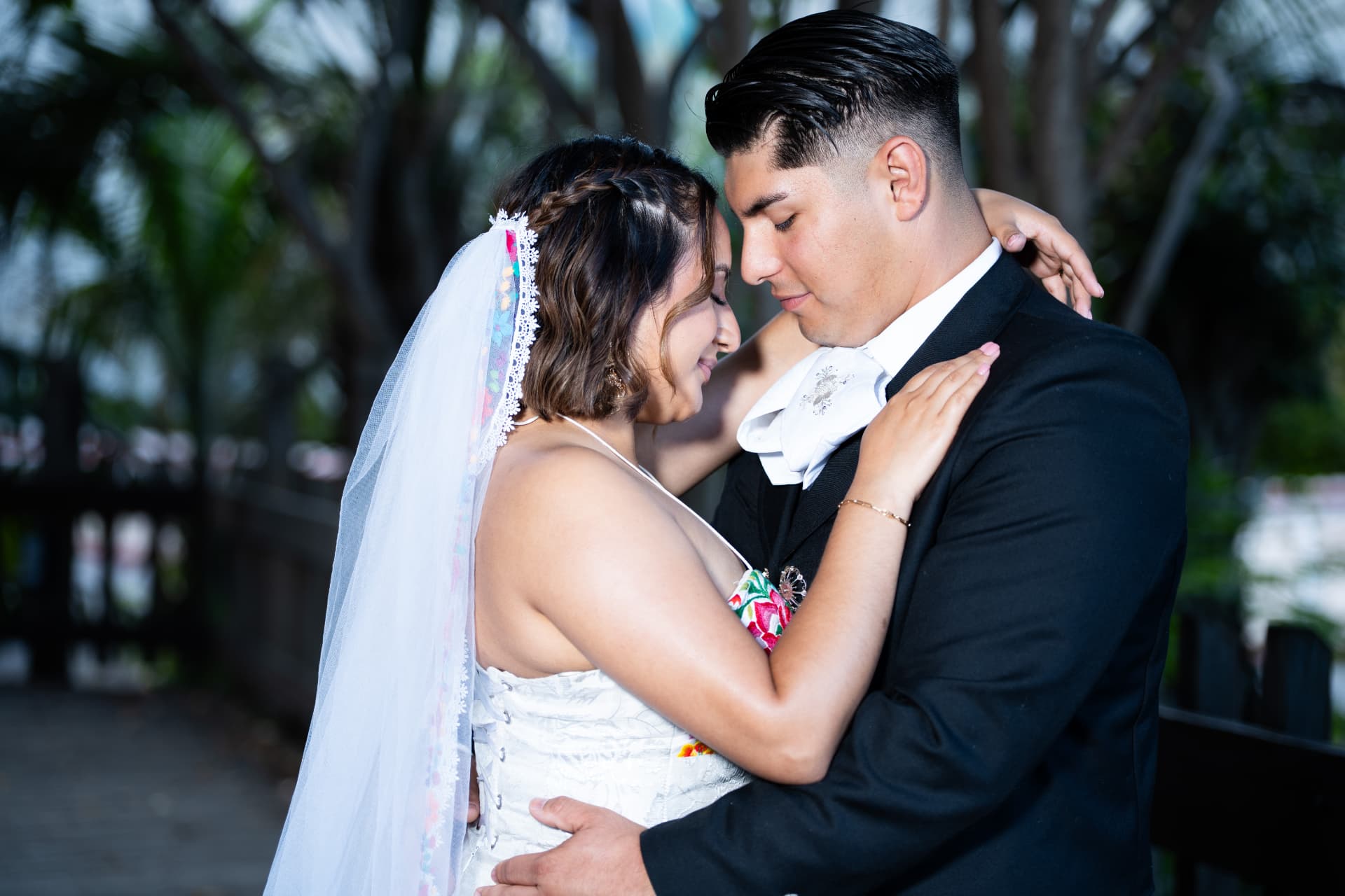 Bride and groom in traditional charro attire hold each other close at golden hour