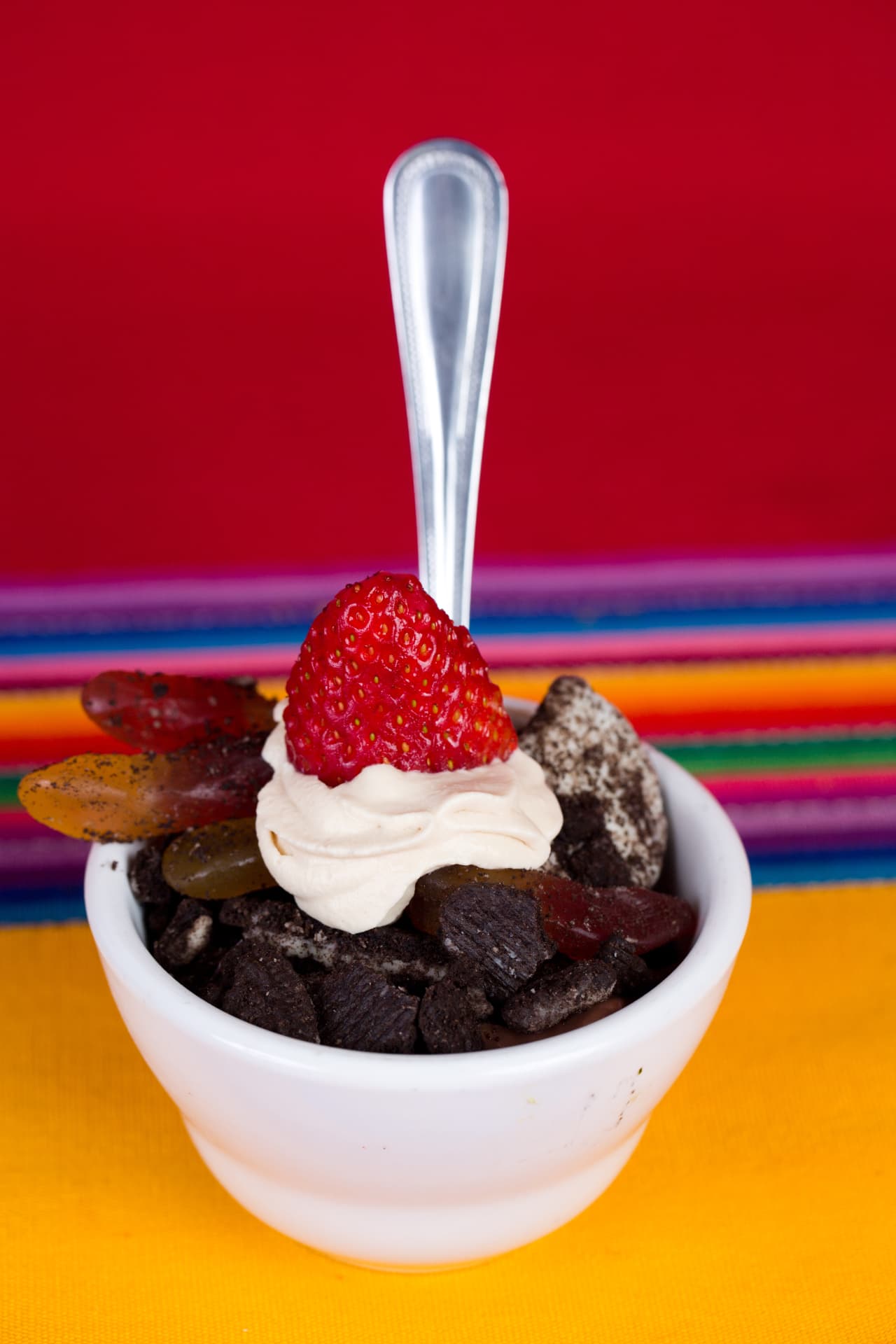 Chocolate cookie dessert topped with cream, a strawberry, and fruit