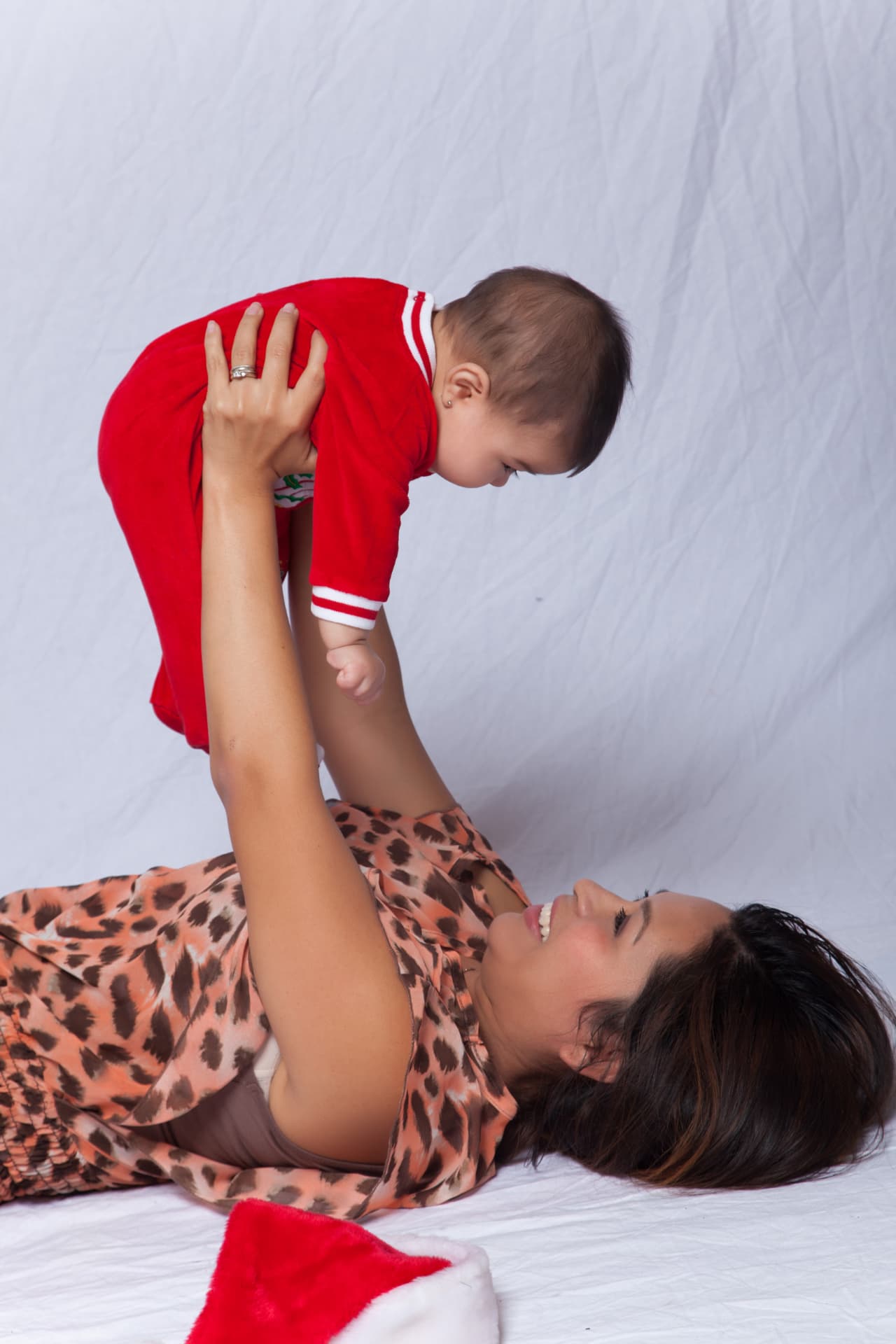 Mother smiling as she lifts her baby during a playful portrait