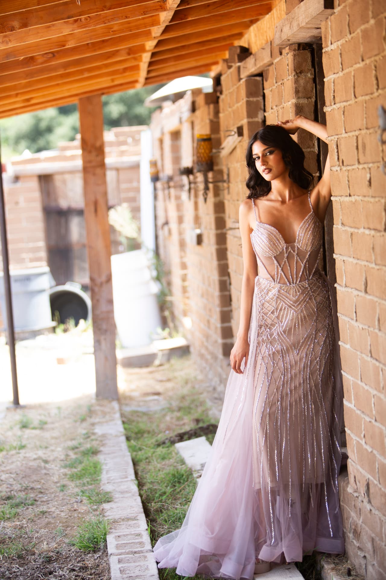 Full-length editorial portrait of a model beneath a rustic brick corridor