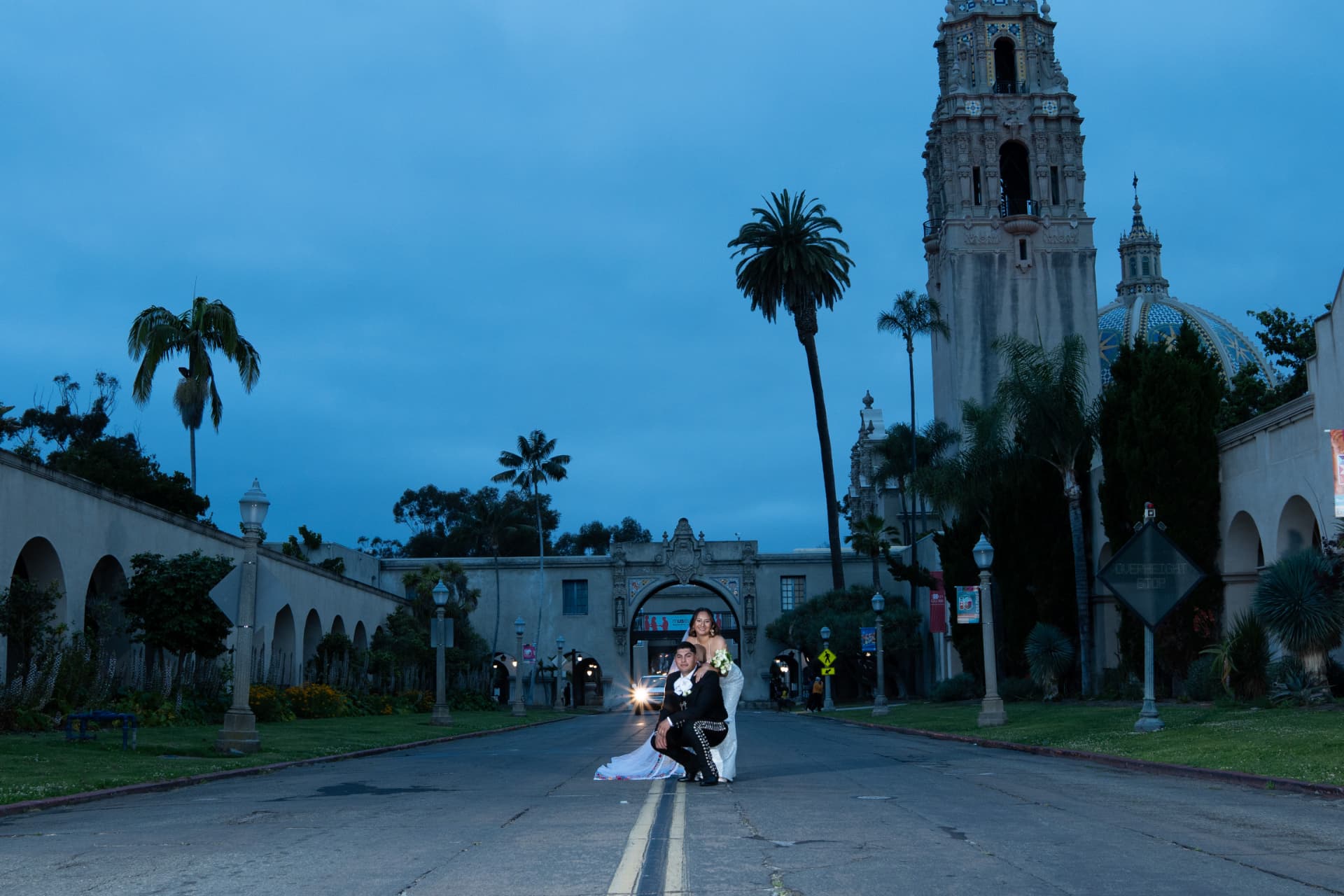 Bride and groom in charro-inspired attire posing on a grand avenue at twilight