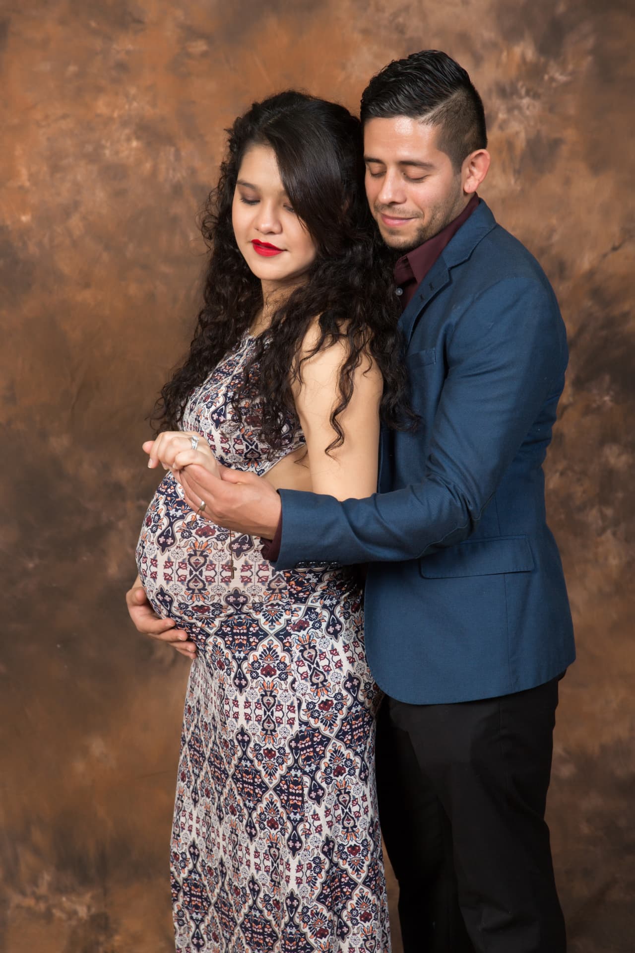 Expectant couple embracing in a warm studio maternity portrait