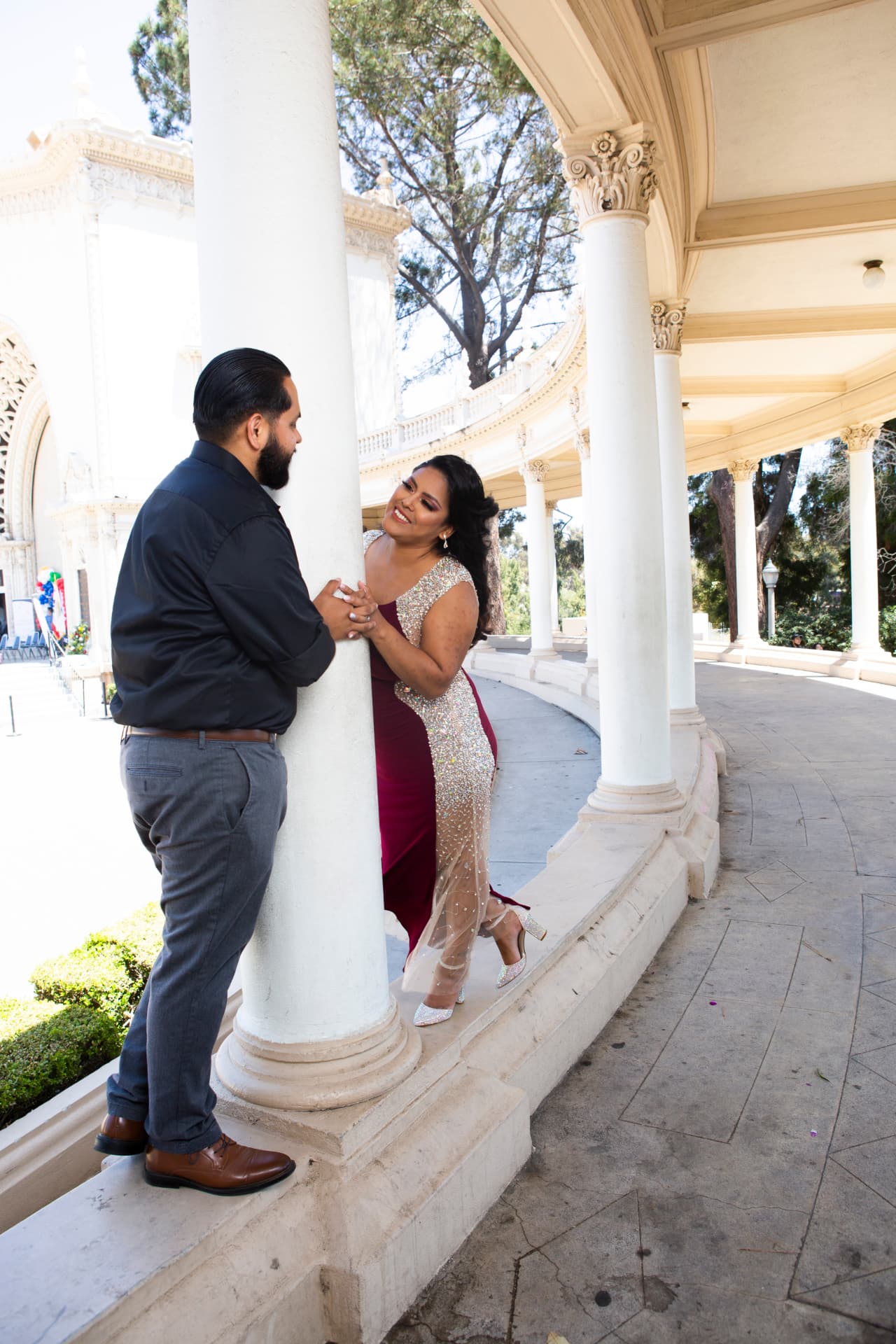 Engaged couple sharing a playful moment among classical columns