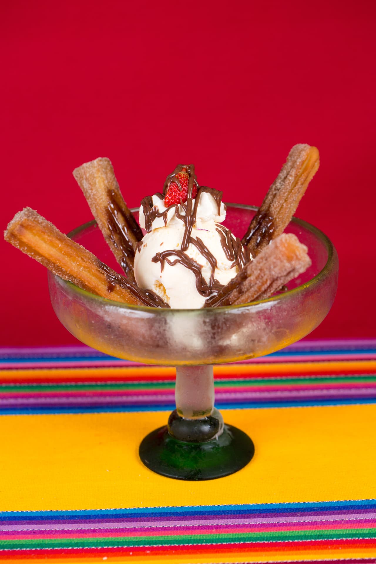 Churro sundae with vanilla ice cream, chocolate drizzle, and a fresh strawberry