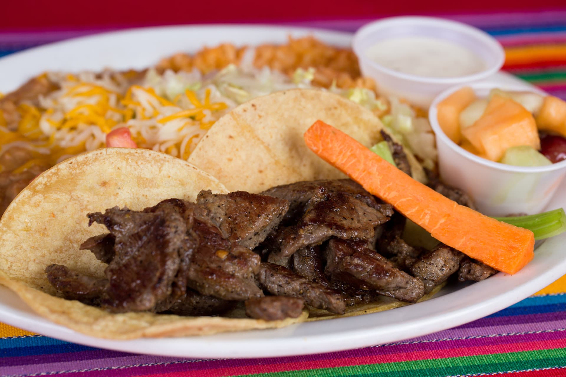 Grilled steak tacos served with rice, beans, fruit, and vegetables