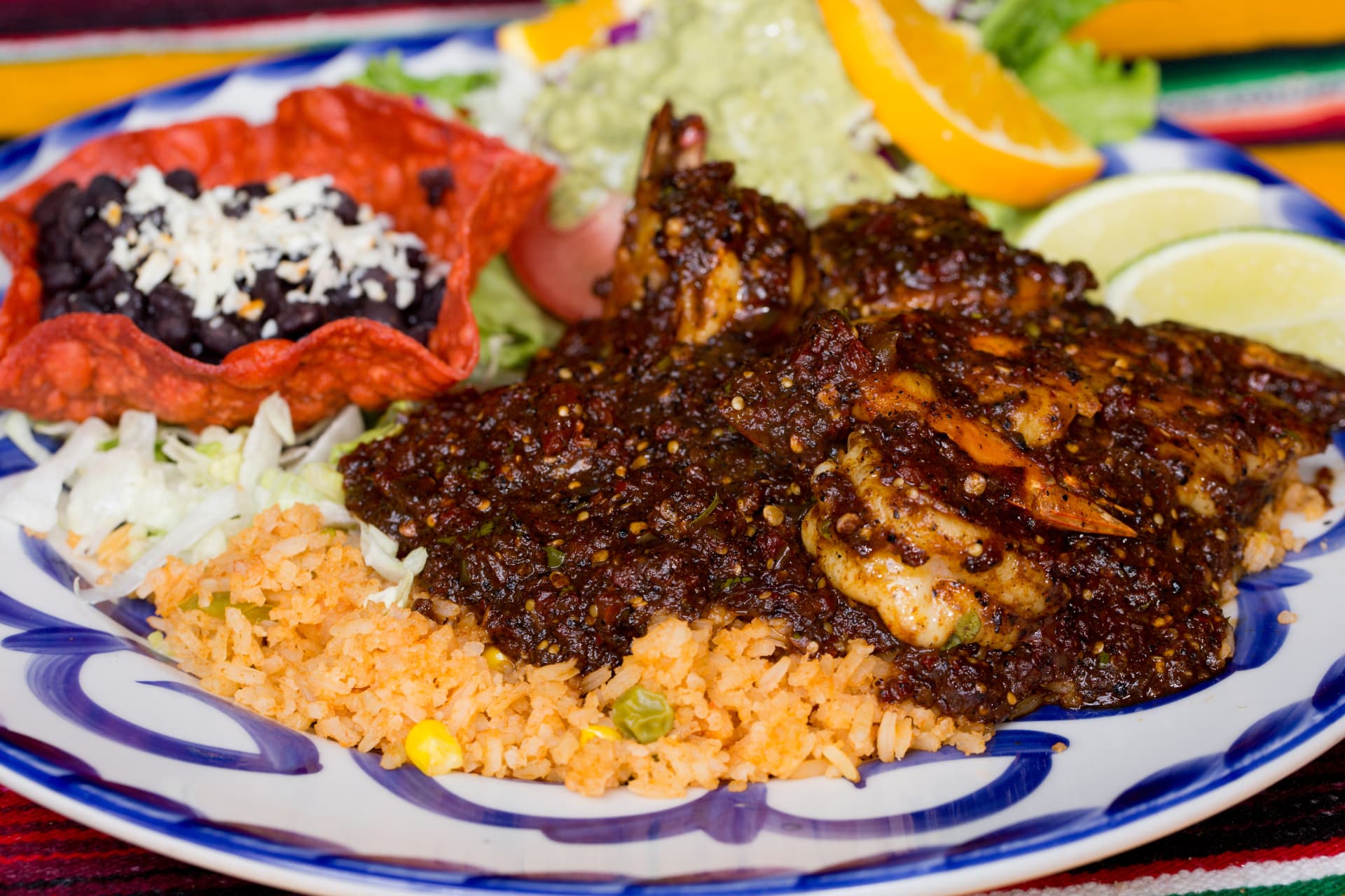 Spicy shrimp in a rich chile sauce served with rice, beans, salad, and guacamole