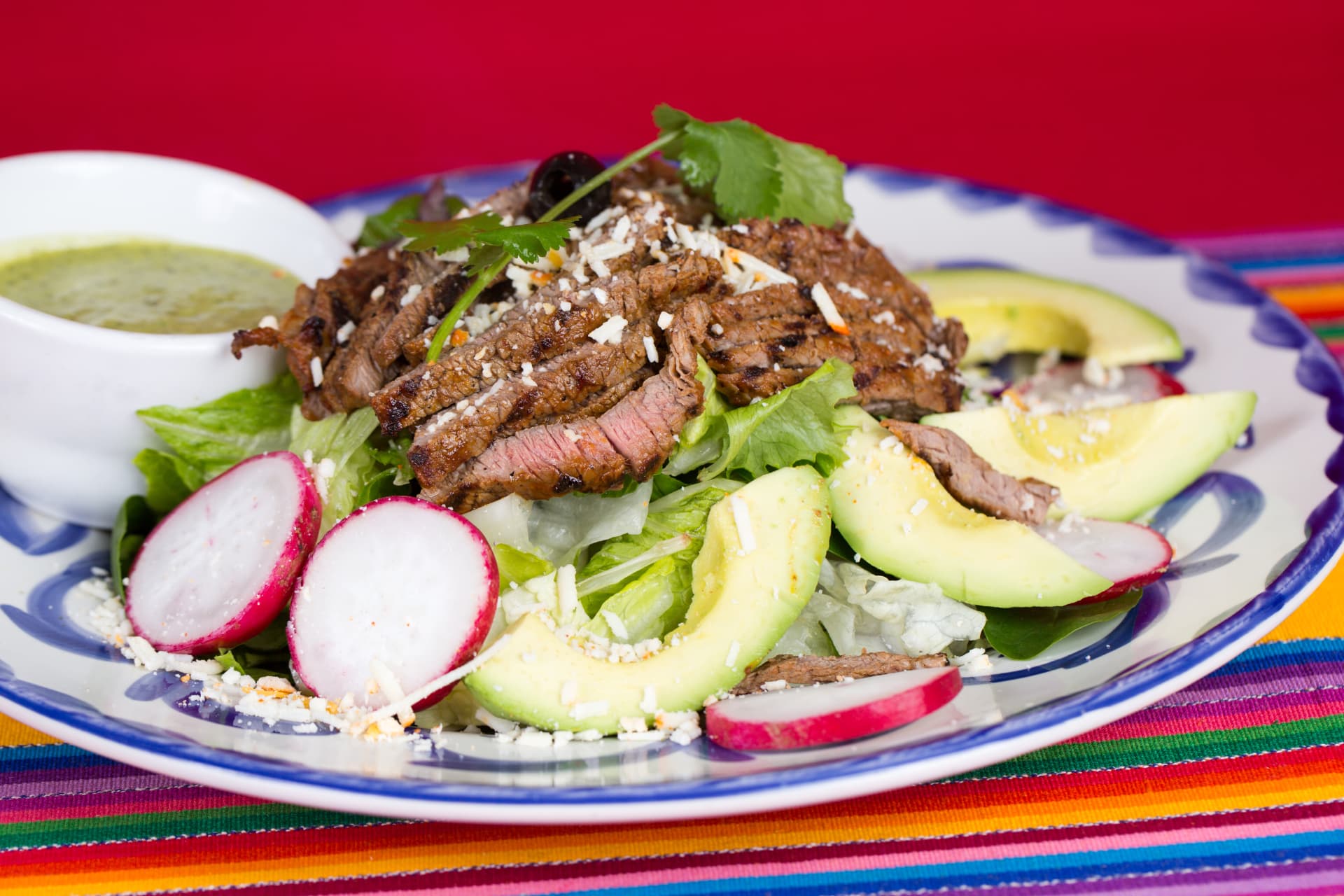Grilled steak salad with avocado, radishes, lettuce, and crumbled cheese