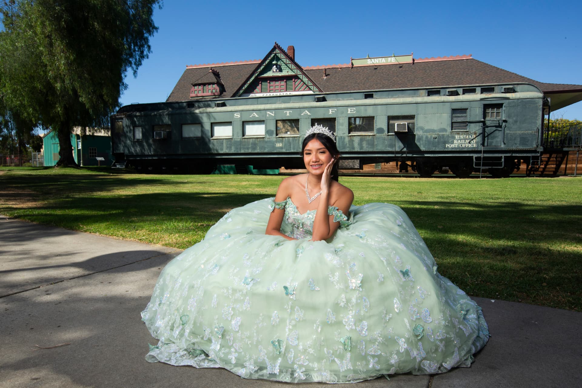 Quinceañera seated in her mint green gown before the historic Santa Fe train