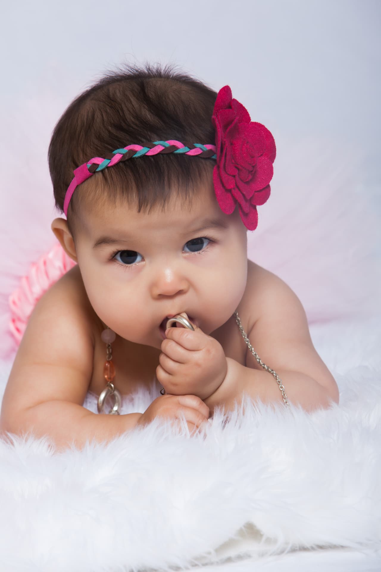 Baby girl wearing a braided pink headband and flower for a close studio portrait
